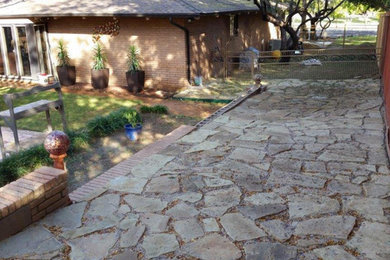 This is an example of a large shade backyard stone landscaping in Austin.