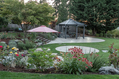 Photo of a large contemporary partial sun backyard stone landscaping in Portland with a fireplace.