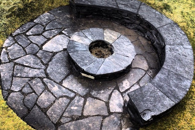 Design ideas for a rustic stone landscaping in Calgary with a fire pit.