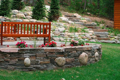Diseño de jardín grande en patio trasero con muro de contención y adoquines de piedra natural