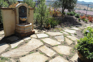 This is an example of a large transitional full sun backyard stone water fountain landscape in Orange County for summer.