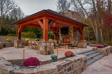 Diseño de patio grande en patio trasero con brasero y adoquines de piedra natural