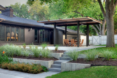 This is an example of a contemporary backyard landscaping in Omaha with a pergola.