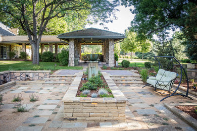 Foto de jardín mediterráneo grande en verano en patio trasero con fuente, adoquines de piedra natural, jardín francés y exposición total al sol