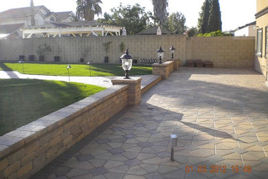 Inspiration for a mid-sized mediterranean backyard concrete paver retaining wall landscape in Los Angeles.