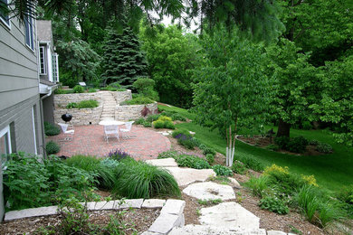 Imagen de jardín clásico de tamaño medio en patio trasero con adoquines de ladrillo