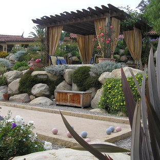 Immagine di un grande giardino mediterraneo dietro casa con un muro di contenimento e ghiaia