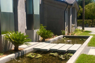 Foto de jardín tradicional grande en verano en patio trasero con jardín francés, estanque, exposición total al sol y adoquines de piedra natural