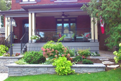 Imagen de jardín contemporáneo de tamaño medio en verano en patio delantero con muro de contención, exposición parcial al sol y adoquines de hormigón