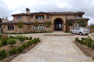 This is an example of a large mediterranean front yard concrete paver driveway in Los Angeles.