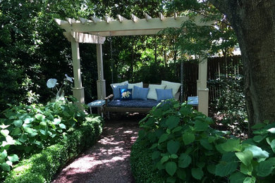 Imagen de jardín clásico en patio trasero con jardín francés y pérgola