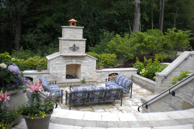 Ejemplo de patio clásico grande en patio trasero con brasero y adoquines de piedra natural
