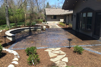 This is an example of a mid-sized traditional partial sun backyard stone landscaping in Detroit with a fire pit.