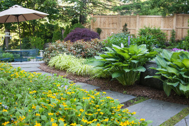 Cette image montre un jardin arrière traditionnel de taille moyenne et l'été avec une exposition ensoleillée et des pavés en pierre naturelle.