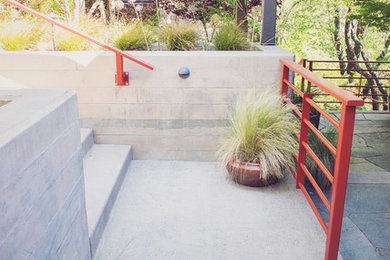 Inspiration for a mid-sized contemporary partial sun front yard stone landscaping in Other.