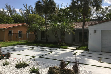 This is an example of a mid-sized contemporary partial sun front yard concrete paver driveway in Miami.