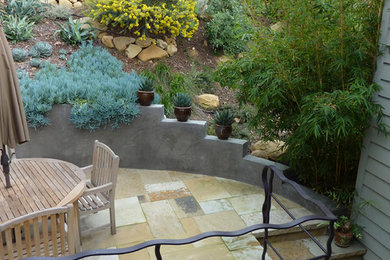 Ejemplo de jardín de secano mediterráneo de tamaño medio en primavera en ladera con muro de contención, exposición total al sol y adoquines de piedra natural