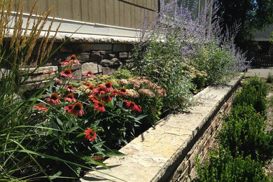 Foto de jardín tradicional renovado de tamaño medio en verano en patio con jardín francés, muro de contención y exposición parcial al sol