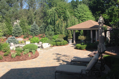 Design ideas for a large contemporary full sun backyard stone landscaping in Boston with a fire pit.