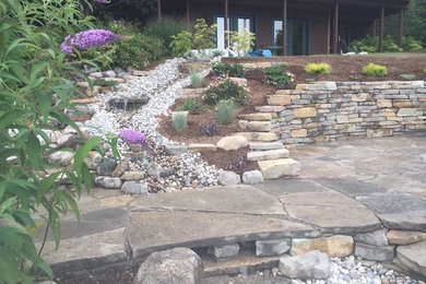 This is an example of a large traditional full sun hillside stone retaining wall landscape in Orange County.