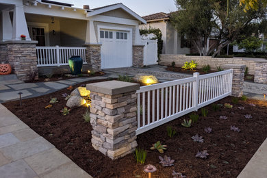 Photo of a mid-sized craftsman full sun front yard stone and vinyl fence landscaping in San Diego.