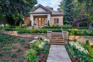 This is an example of a large classic front formal full sun garden in Denver with a retaining wall and natural stone paving.