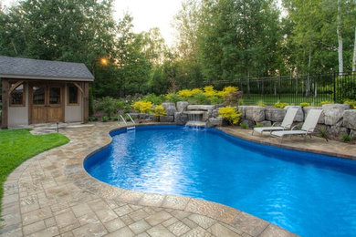 Foto de piscina con fuente rústica de tamaño medio en patio trasero con adoquines de hormigón