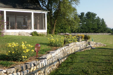 This is an example of a farmhouse full sun backyard retaining wall landscape in DC Metro.