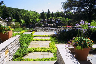 Klassisk inredning av en stor trädgård i full sol, med en fontän och naturstensplattor på sommaren