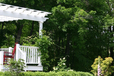 Diseño de jardín de estilo americano de tamaño medio en verano en patio trasero con jardín francés, muro de contención, exposición parcial al sol y mantillo