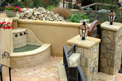 Imagen de jardín tradicional renovado de tamaño medio en patio trasero con fuente, exposición total al sol y adoquines de piedra natural