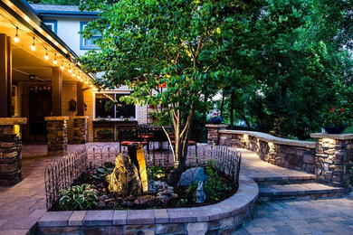 Ejemplo de jardín tradicional en patio trasero con fuente y adoquines de piedra natural