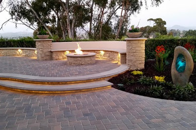 Inspiration for a mid-sized contemporary backyard stone landscaping in San Diego with a fire pit.