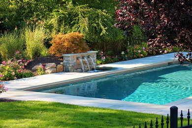 Modelo de jardín clásico renovado grande en patio trasero con fuente, exposición parcial al sol y adoquines de piedra natural