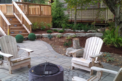 This is an example of a large contemporary partial sun backyard stone landscaping in Toronto with a fire pit.