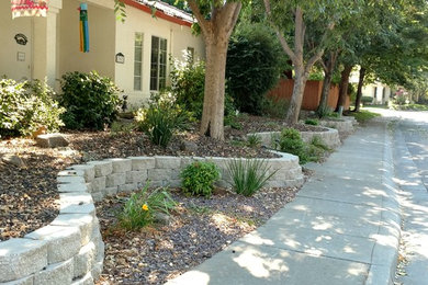 Diseño de jardín clásico de tamaño medio en patio delantero con muro de contención y gravilla