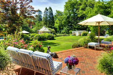 Imagen de jardín actual grande en patio trasero con jardín francés, exposición total al sol y adoquines de ladrillo