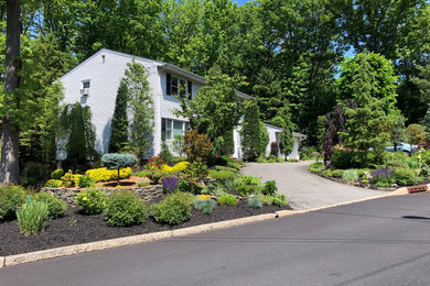 This is an example of a large full sun front yard retaining wall landscape in New York.