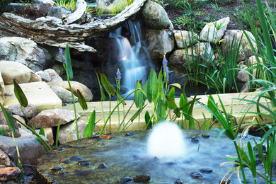 Inspiration for a mid-sized traditional backyard stone water fountain landscape in Other.