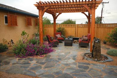 Ejemplo de patio de estilo americano grande en patio trasero con pérgola, fuente y gravilla
