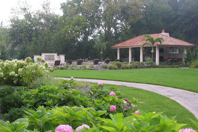 Modelo de jardín clásico en patio trasero con fuente y adoquines de ladrillo