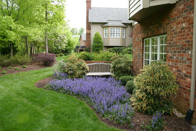 Foto de jardín tradicional de tamaño medio en primavera en patio trasero con muro de contención y exposición total al sol