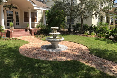 Design ideas for a medium sized classic front formal partial sun garden in Orlando with a water feature and brick paving.