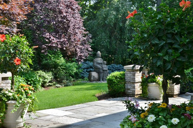 Modelo de jardín tropical de tamaño medio en verano en patio trasero con jardín francés, exposición parcial al sol y adoquines de hormigón