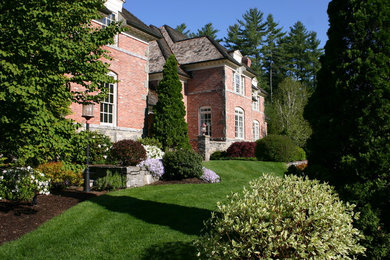 Modelo de jardín clásico de tamaño medio en primavera en patio trasero con jardín francés, muro de contención, exposición parcial al sol y mantillo