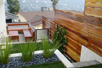 This is an example of a medium sized contemporary sloped formal partial sun garden in Los Angeles with a retaining wall and gravel.