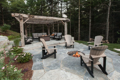 Mountain style backyard stone patio photo in Toronto with a fire pit