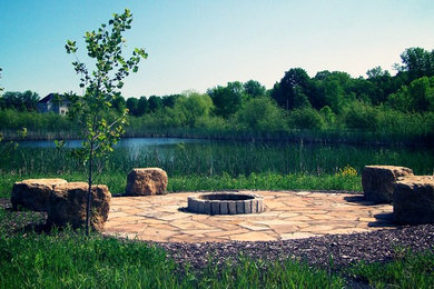 Großer Uriger Garten im Sommer, hinter dem Haus mit direkter Sonneneinstrahlung, Feuerstelle und Natursteinplatten in Minneapolis