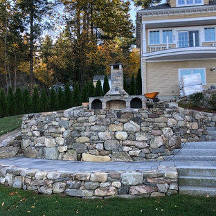 Großer Stilmix Hanggarten im Sommer mit Kamin, direkter Sonneneinstrahlung und Pflasterklinker in Boston