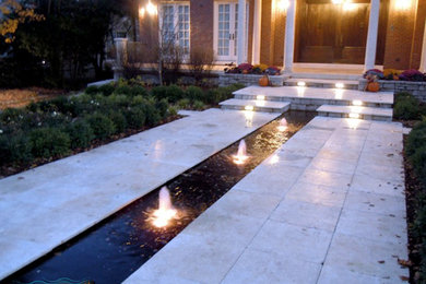 Exempel på en mellanstor modern trädgård framför huset, med en fontän och naturstensplattor